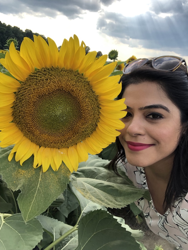 A giant sunflower in a field with a girl's face next to it